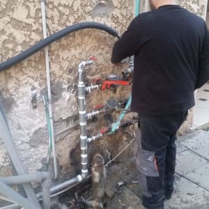 אדם עובד על צנרת עם מפתח צינורות