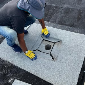 אדם מתקין יריעת איטום על גג עם חור