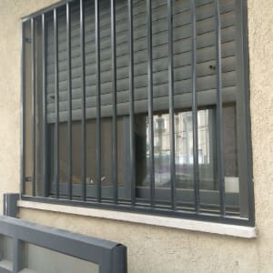 סורגי מתכת על חלון עם תריסים סגורים
