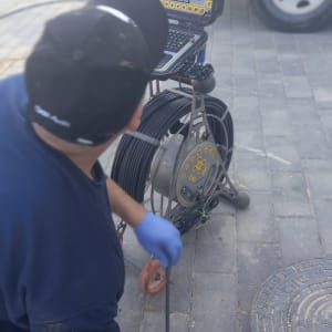 אדם משתמש במצלמה לאיתור נזילות בביוב