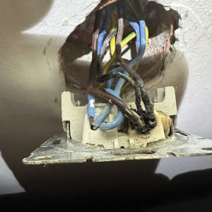 חוטי חשמל צבעוניים יוצאים מקיר עם חור