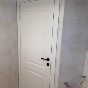 דלת לבנה עם ידית שחורה בחדר אמבטיה