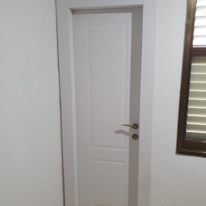 דלת לבנה עם ידית מתכת בחדר