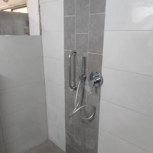 מקלחת חדשה עם אריחים אפורים וברזים מודרניים