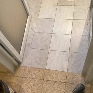 רצפת חדר אמבטיה עם פתח ניקוז ופטיש על הרצפה