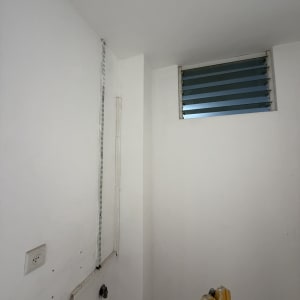 קיר לבן עם חלון קטן וסולם צהוב