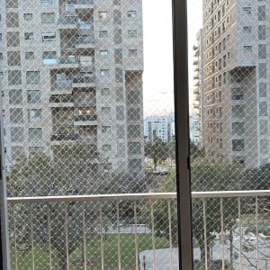 רשת הגנה על חלון עם נוף לבניינים ועצים