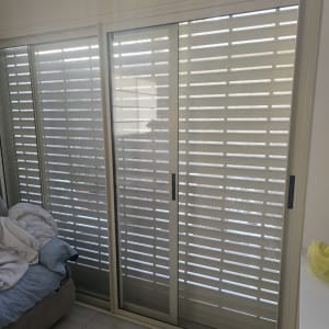 תריסים לבנים בחלון זכוכית גדול