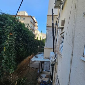 חצר עם צמחייה ומבנה עם מזגן על הקיר