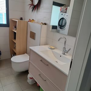 חדר רחצה ושירותים מסודר ונקי עם ארון כיור ומדף עץ