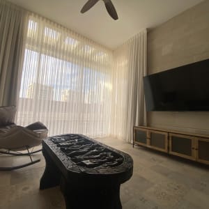 וילונות לבנים בחדר עם כורסה ושולחן מעוצב