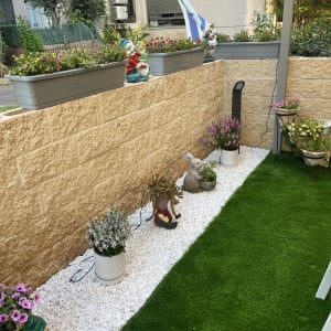 עציצים עם פרחים צבעוניים על אדן אבן בגינה