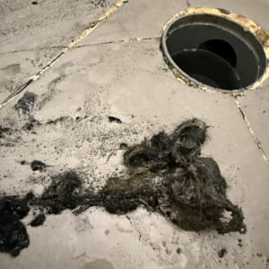 ניקוי ניקוז עם לכלוך ושיער על רצפה רטובה