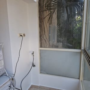 מרפסת עם חלון גדול וצמחייה בחוץ