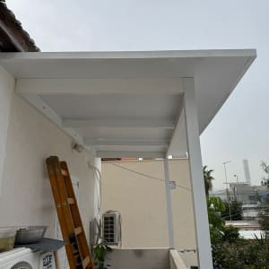 פרגולה מאלומיניום על מרפסת עם סולם ועציץ