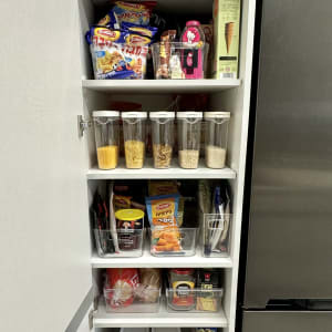 ארון מטבח מאורגן עם קופסאות פלסטיק ומוצרי מזון שונים