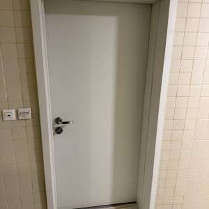 דלת לבנה עם ידית מתכת על קיר מרוצף