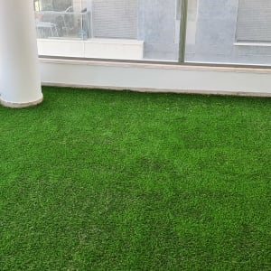 דשא סינתטי על מרפסת עם מעקה זכוכית