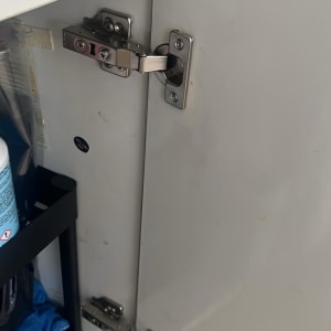 צירי מתכת מותקנים על דלתות ארון עץ לבן