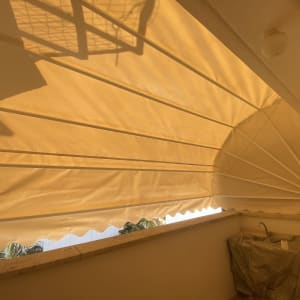 סוכך בד מתוח מעל מרפסת עם צללים גיאומטריים.