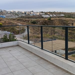 מרפסת נקייה עם מעקה זכוכית שקוף וריצוף חוץ