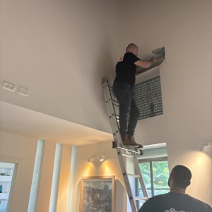 אדם על סולם מתקין תריסים בחדר מואר