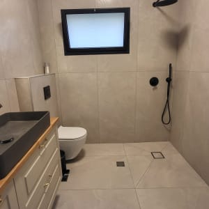 חדר אמבטיה משופץ עם מקלחת, כיור ושירותים