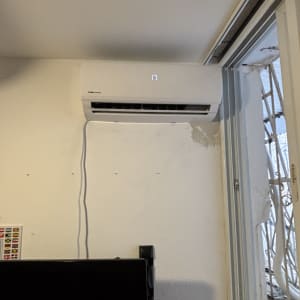 מזגן מותקן על קיר ליד חלון פתוח