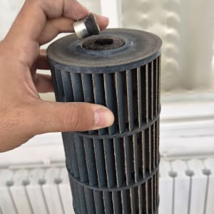 יד מחזיקה חלק ממזגן על רקע חלון