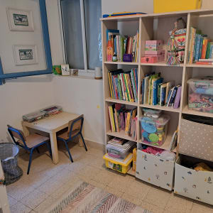 חדר ילדים עם מדפים מלאים בספרים וצעצועים