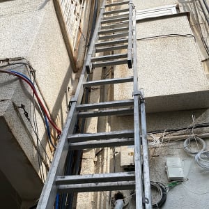 סולם מתכת ליד צינורות חיצוניים על קיר בניין