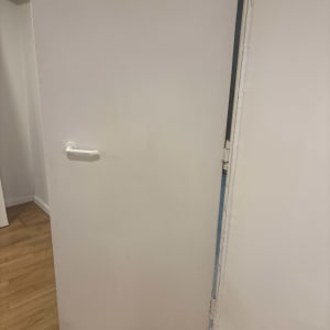 דלת פתוחה עם ידית לבנה על רצפת עץ