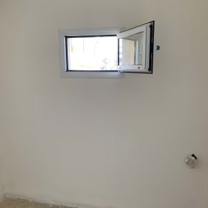 חלון אלומיניום קטן פתוח בקיר לבן