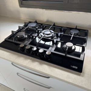 כיריים גז שחורות עם חמישה מבערים במטבח מודרני