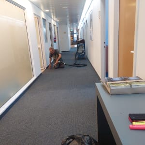 אדם מנקה שטיח במסדרון עם שואב אבק