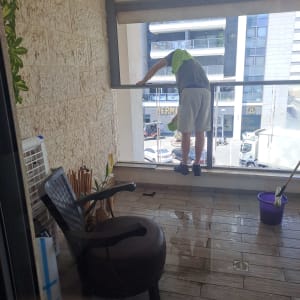 אדם מנקה חלון במרפסת עם דלי ומגב
