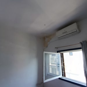 קיר עם סימני רטיבות ליד מזגן וחלון פתוח