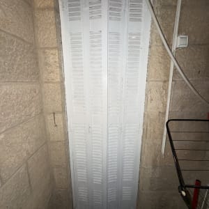 דלת מתקפלת לבנה בקיר אבן
