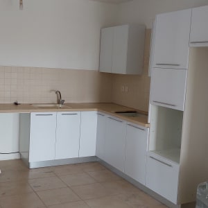 מטבח עם ארונות לבנים ומשטח עבודה בהיר