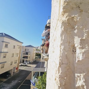 אדם עם קסדה עובד על קיר גבוה עם חבלים