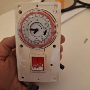 טיימר חשמלי עם מתג אדום ביד חשמלאי