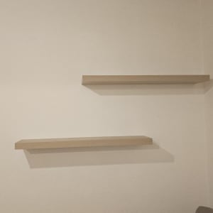 מדפים תלויים על קיר מעל ספה אפורה