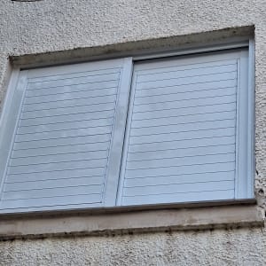 חלון אלומיניום עם תריסים סגורים בקיר חיצוני