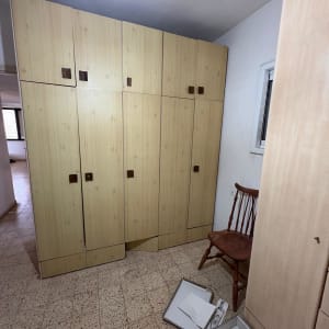 חדר עם ארון עץ וכיסא, קופסאות על הרצפה