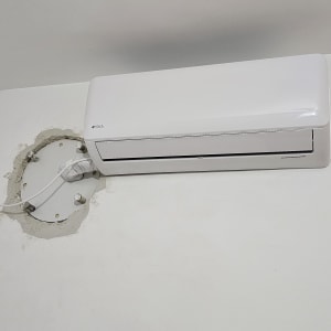 מזגן מותקן על קיר לבן עם חוטים חשופים