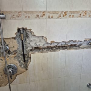 קיר אמבטיה עם צנרת חשופה ותיקון אינסטלציה