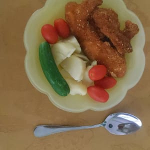 צלחת עם ירקות, עוף מטוגן וכף על שולחן
