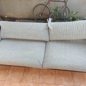 ספה אפורה בחצר עם אופניים ברקע