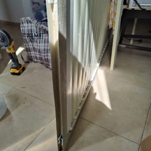 תריס מתכת עומד על רצפה, עם גלגלים קטנים בתחתית.