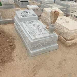 מצבות בבית קברות עם פרחים על אחת מהן